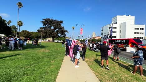 trump supports in beverly hills park with rally flags and banners waving to people in cars passing by