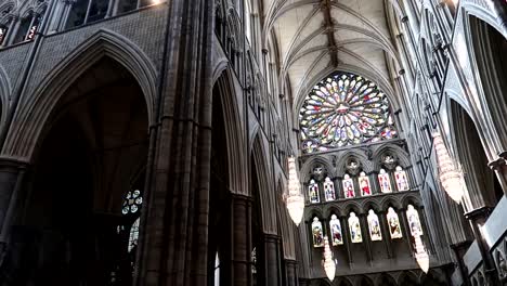 dentro da abadia de westminster com uma grande roseta de vitrais no topo