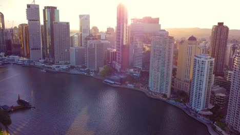 Tilting-up-aerial-view-of-a-modern-city-with-tall-buildings-and-bright-sky-during-sunset