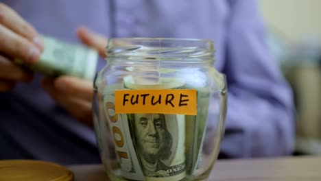 caucasian man putting a glass jar put in a drawer table with his savings for future