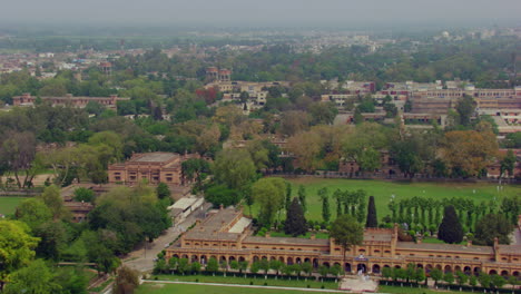 Conducción-De-Drones-De-La-Ciudad-Limpia-Y-Verde-Que-Pasa-Por-Encima-De-Los-Antiguos-Edificios-Patrimoniales,-árboles-Y-Una-Mezquita-Blanca