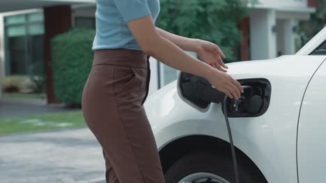 progressive woman unplugs the electric vehicle's charger at his residence.