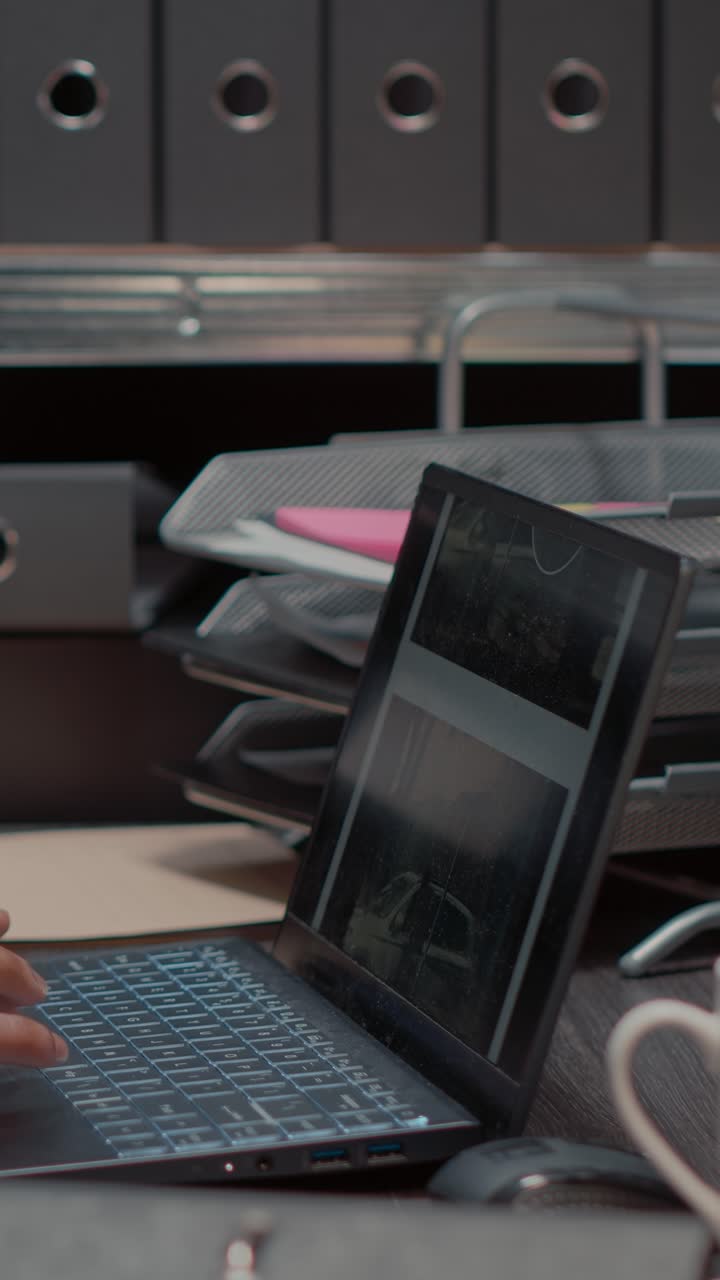Vertical video: African american man examining photos on laptop