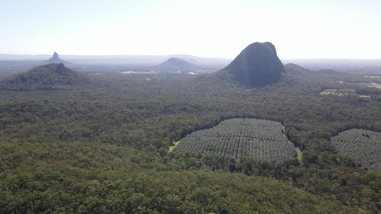 Drone aerial panning down over the glasshouse mountains and a crop field