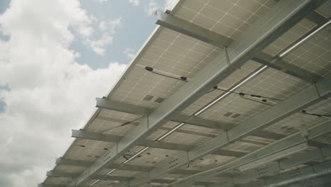 bottom up shot of solar panels from below against blue sky and sun outdoors,close up