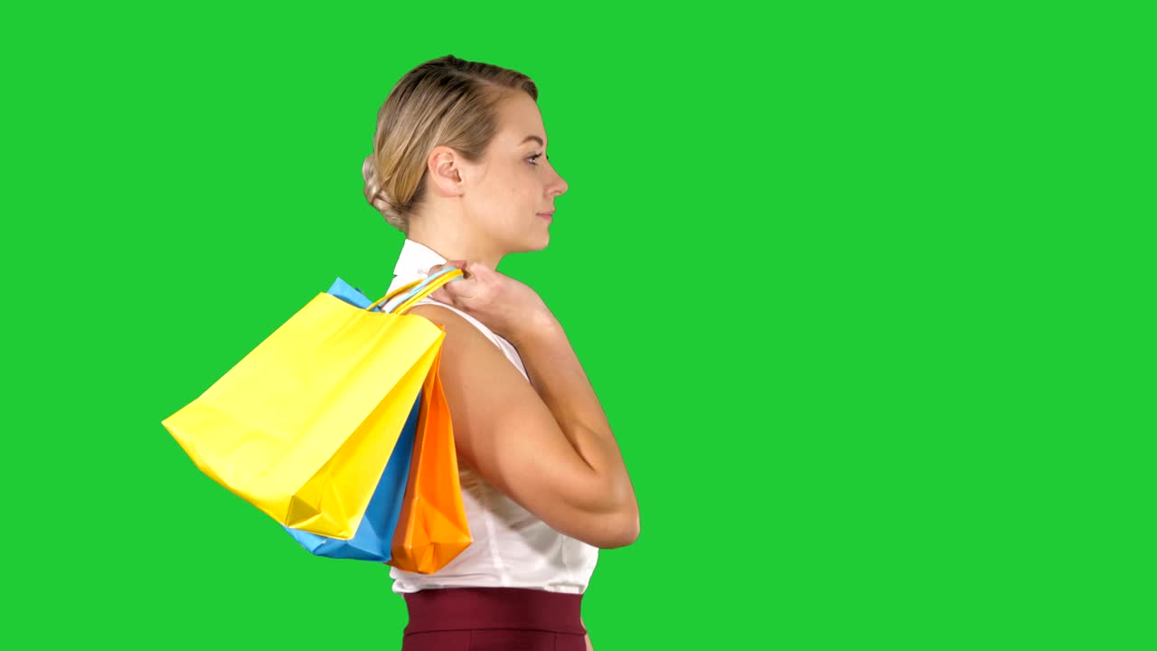 Young happy woman with shopping bags walking on a Green Screen, Chroma Key