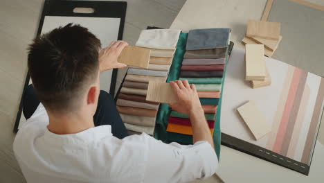 creative professions - designer beats samples of fabric and wood, compares color and shade