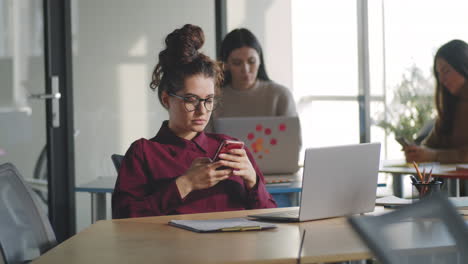 female office worker using smartphone at desk