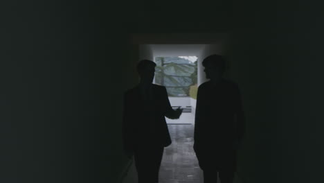 두 명의 사업가들이 어두운 복도를 고 있습니다.