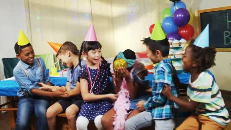 animation of gold confetti over diverse happy children having fun at party with hats and balloons