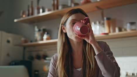 online student drinking coffee at home kitchen close up. woman looking laptop