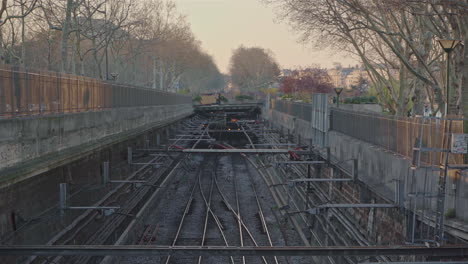 pan down of a train moving slowly into frame on the railway lines in the middle of the city of paris in france