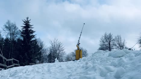 snow guns, snow lance switched off in white snow landscape on a slope with trees in the background