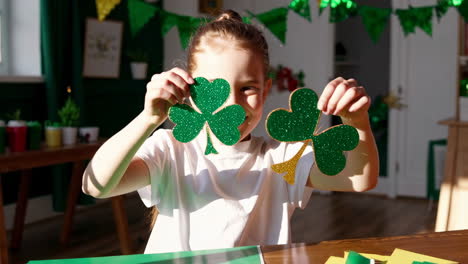 child making and showing st. patrick's day shamrock crafts