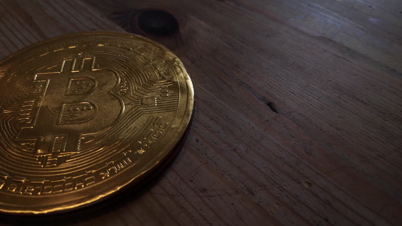 Wrapped chocolate gold bitcoin crypto currency concept on wooden kitchen table right orbit top down shot