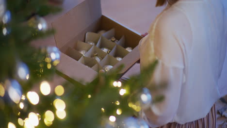 woman unpacks iconic handmade glass baubles for tree decoration