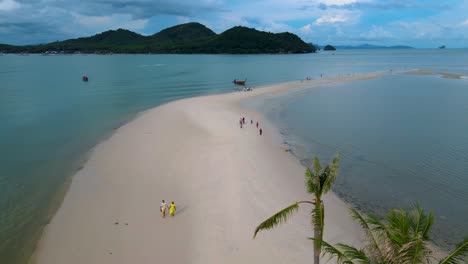 couple of men and women walking on the beach at the island koh yao yai thailand, beach with white sand and palm trees.