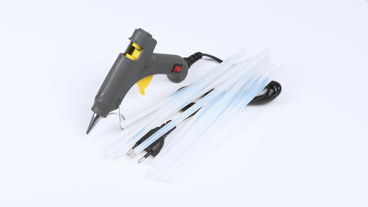 pistola de pegamento eléctrico caliente y palo de silicona aislados en blanco. vista lateral. movimiento de bucle. rotación 360.