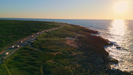 coastal road summer sunset over rocky shore. drone view cars riding on seashore.