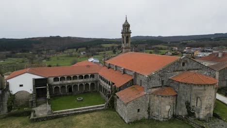 drone rises above santa maria de xunqueira monastery to reveal farmland fields of ourense