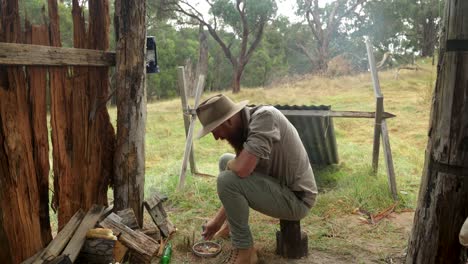 a bushman eating meat stew in a historical bark hut in the australian bush