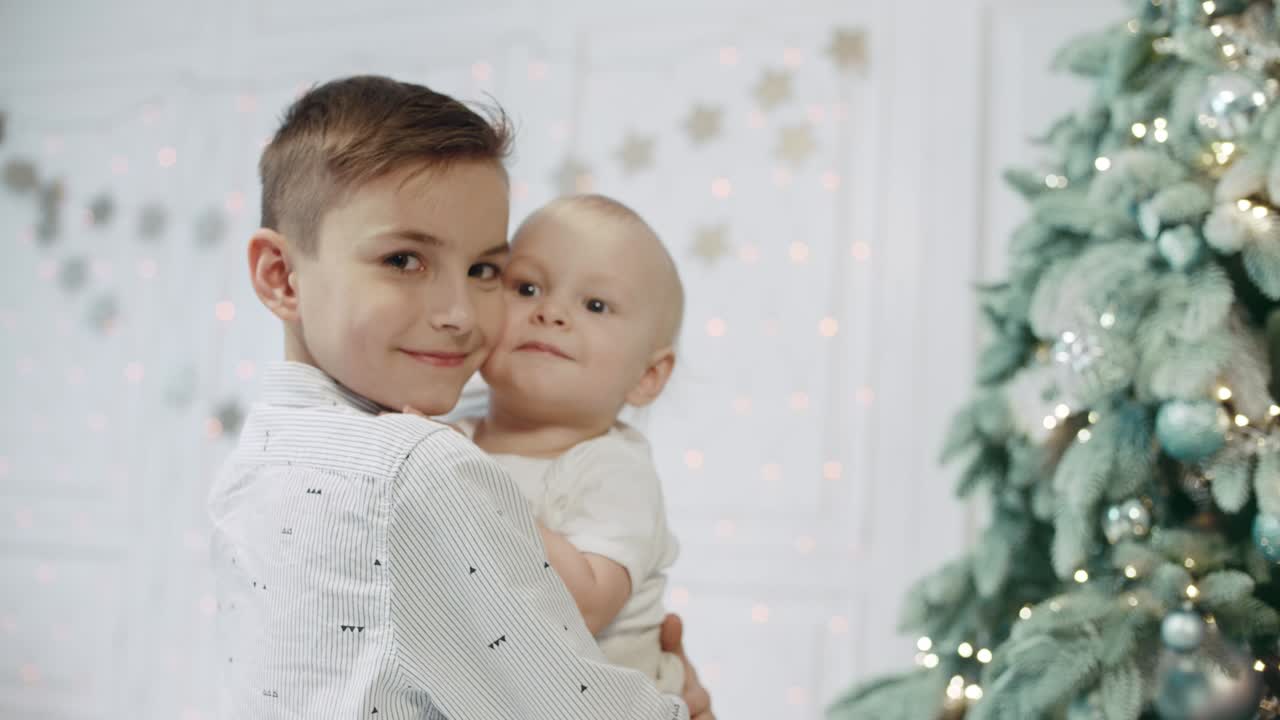 Ritratto di fratelli felici vicino all'albero di Natale in una casa moderna.