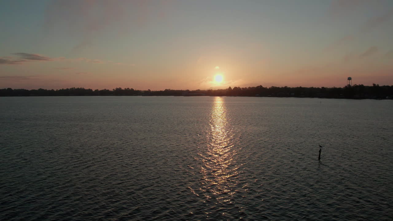 Beautiful drone shot into the sun rising over a lake with reflection