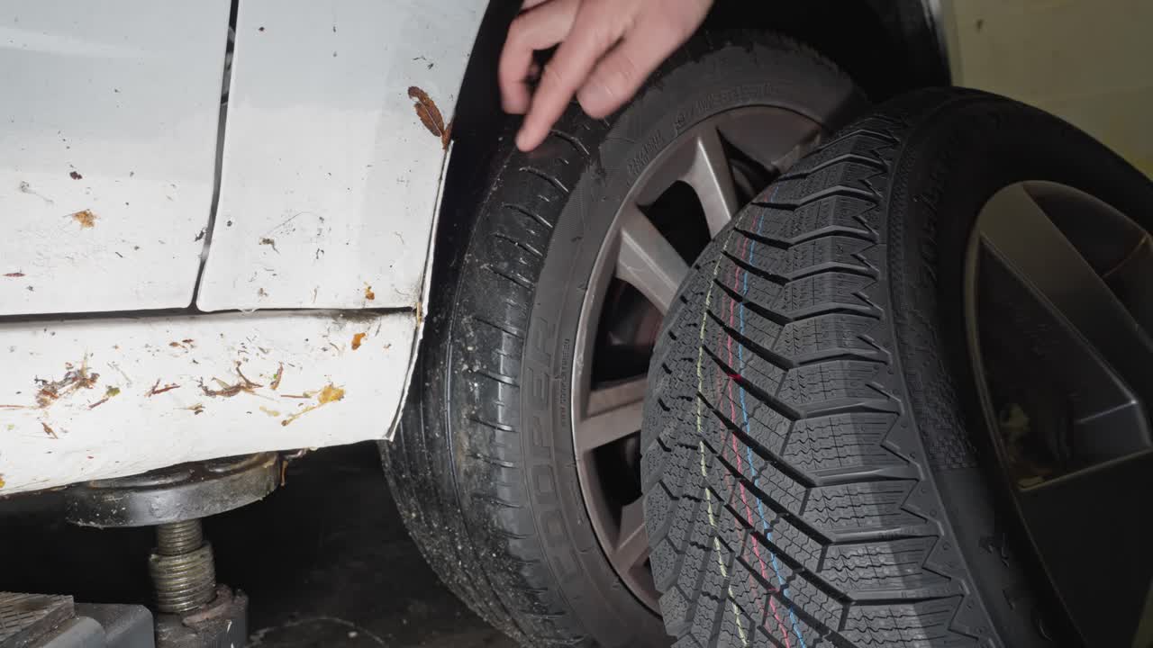 Hand examines tread depth on old summer tire and new winter tire emphasizing safety and maintenance awareness