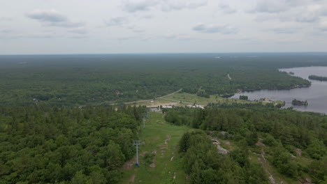 aerial shot over green tree covered mountain with lake along coast. calabogie ski hill. ontario canada