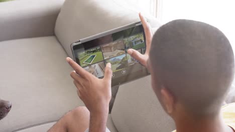 hombre biracial usando una tableta con vistas de cámaras de seguridad en la pantalla, cámara lenta