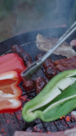 grilling sausages, meat, and peppers on a hot grill