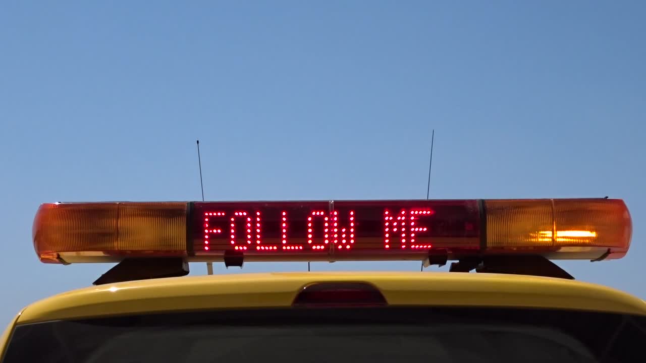 coche de marshaller del aeropuerto que muestra un signo brillante de sígueme con espacio para texto o logotipo