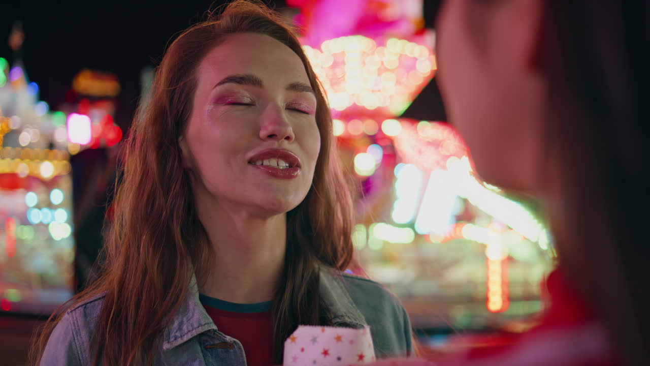 재미있는 소녀는 조명 카루셀에서 간식을 먹습니다. 편안한 십대 대화