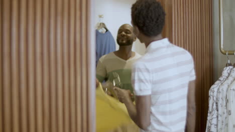 handsome black man trying on t-shirts in dressing room.