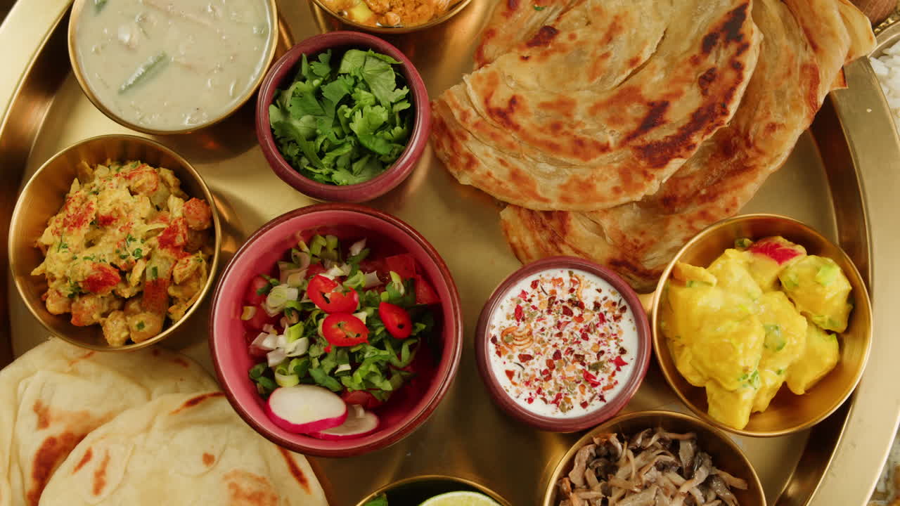 A vibrant platter featuring a variety of traditional Indian dishes, including curries, chutneys, and flatbreads.