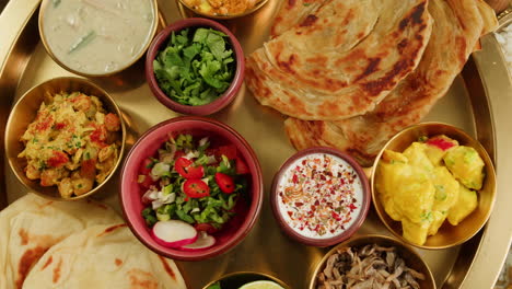 a vibrant platter featuring a variety of traditional indian dishes, including curries, chutneys, and flatbreads.