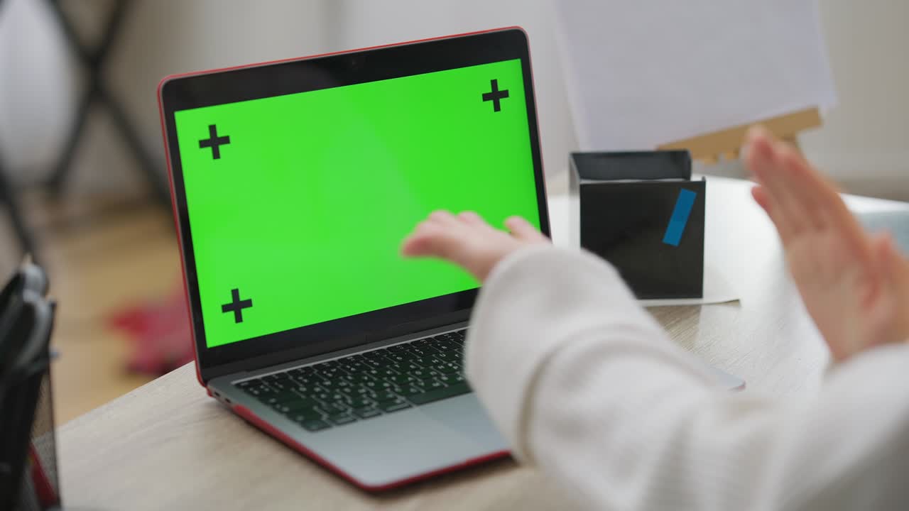 primer plano de una computadora portátil con pantalla verde en la mesa con manos femeninas gestando. joven caucásica irreconocible usando lenguaje de señas frente al dispositivo chromakey. maqueta y sordera.