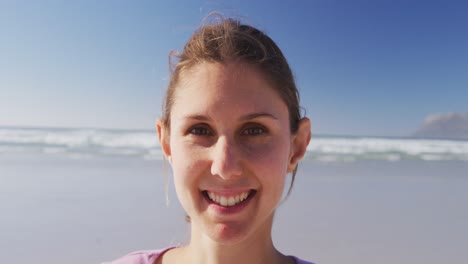 Mujer-Caucásica-Mirando-La-Cámara-Y-Sonriendo-En-La-Playa-Y-El-Fondo-Del-Cielo-Azul