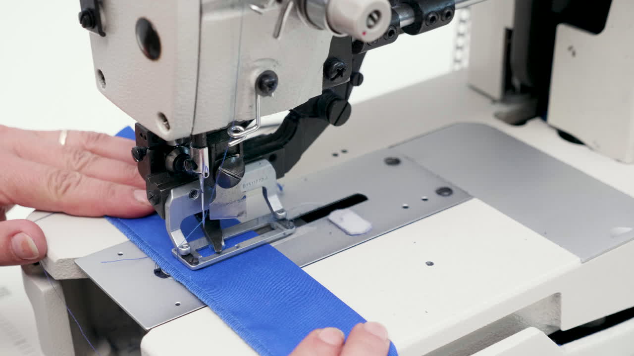 Female worker using a sewing machine to cut holes for buttons