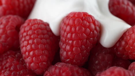 frambuesas vertidas con yogur - un líquido espeso cubre la fruta en cámara lenta
