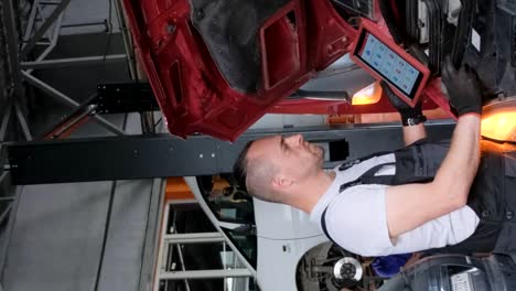 auto mechanic performing diagnostics and repair on a car in a garage