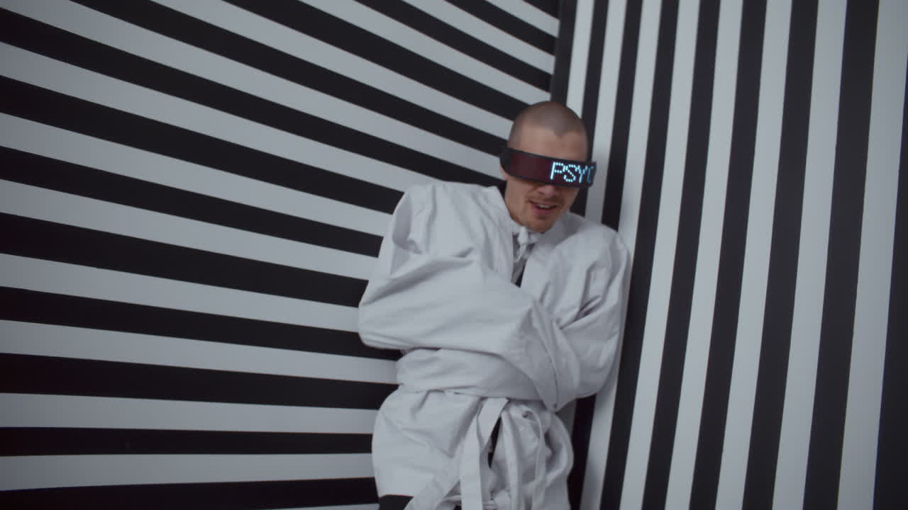 Man in VR Glasses and Straight Jacket in Striped Room