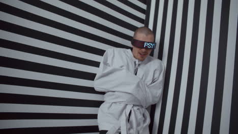 man in vr glasses and straight jacket in striped room