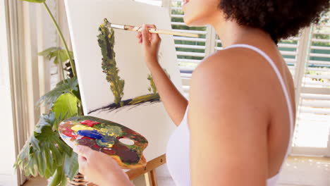 painting on canvas, woman holding palette and brush in bright room