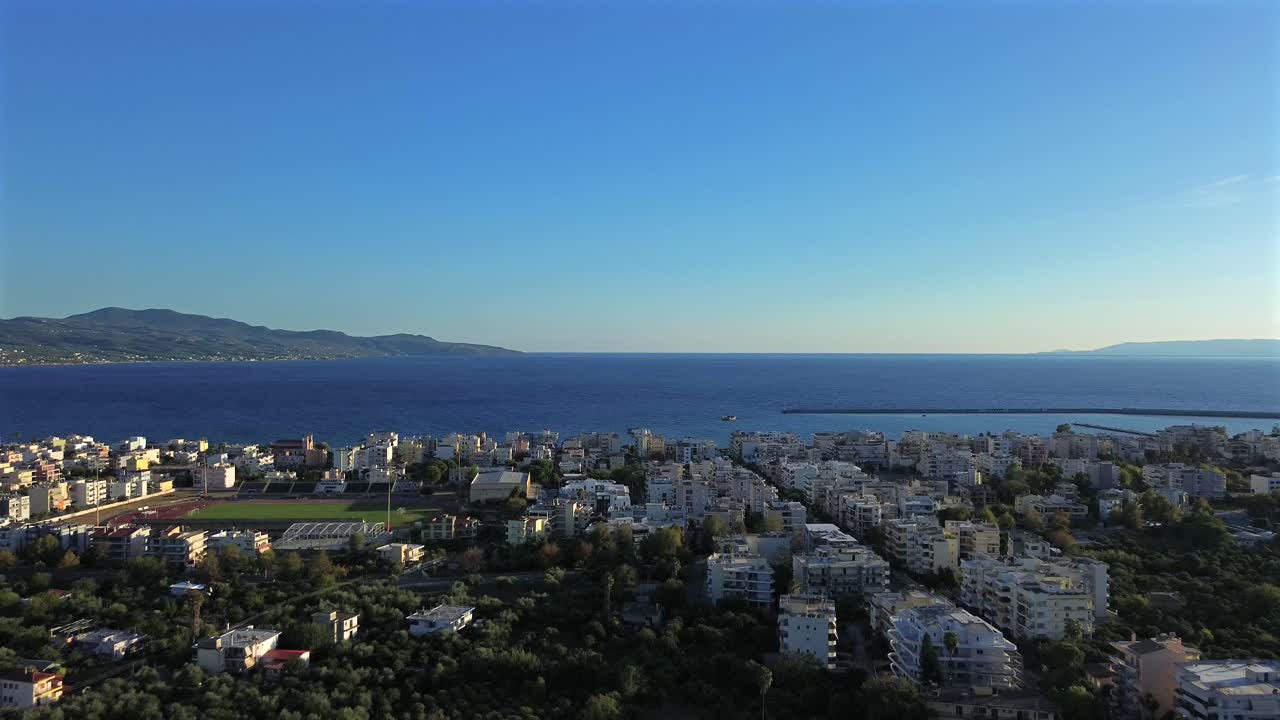 Aerial push in shot, revealing Messinian Gulf, over Kalamata's cityscape on a clear blue sky autumn day 4K