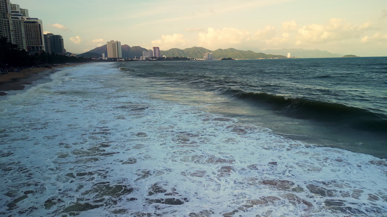 Ondas do Oceano Quebrando em uma Praia Urbana Costeira com Montanhas
