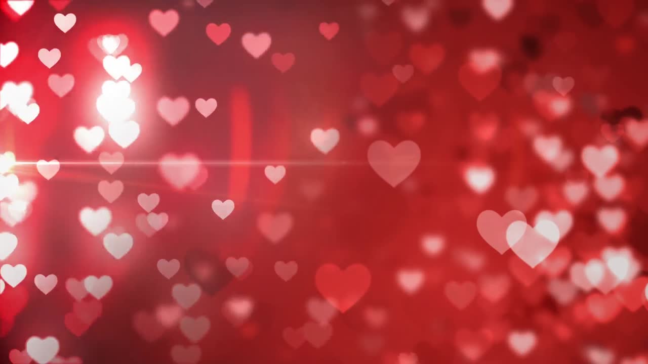 animación de corazones rojos brillantes cayendo sobre un fondo oscuro.