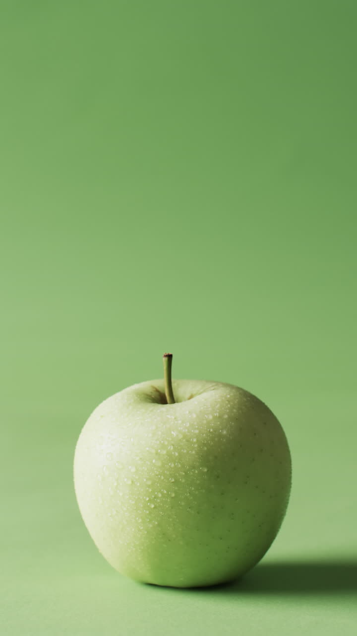 Vertical video of green apple with copy space over green background