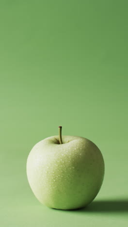 vertical video of green apple with copy space over green background