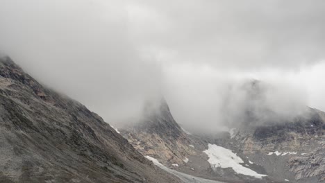 cold fog and clouds rush over and down rocky steep mountain slopes